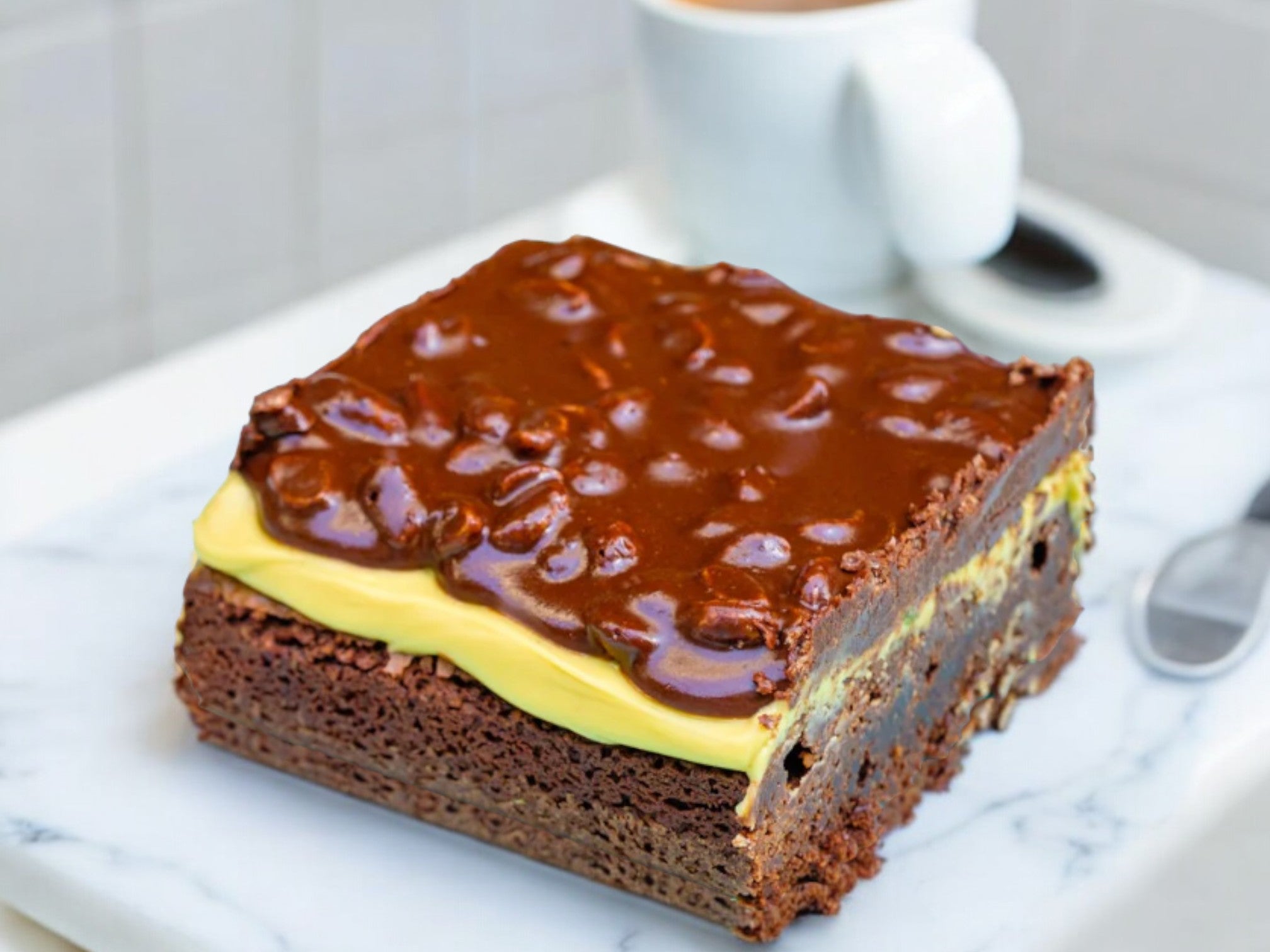 pistachio brownie topped with pistachio cream and chocolate ganache